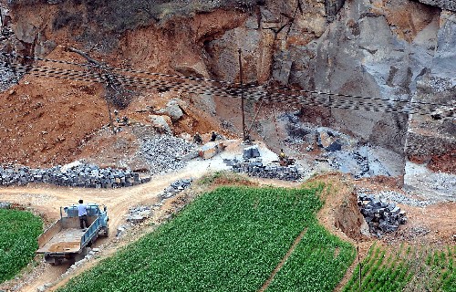 非法炸山取石 嵩山生态环境破坏严重 嵩山北麓的一个采石场上摆放着准备运走的石料(4月3日摄)。 在河南省登封市和偃师市交界处的偃师市府店镇唐窑村。村庄对面的整座山体被挖的“千疮百孔”,采石场和石材加工点随处可见。 当地群众告诉记者,这座山是嵩山少林寺背依的少室山北麓。为了躲避检查,采石者由原先在路边开采,转移到大山深处。为了加快开采进度,他们采取了对山体破坏性极大的炸山取石法,昔日种植的松柏等树木也随着日益推进的开采而被毁掉。 2007年1月,国家建设部曾对嵩山风景名胜区违法违规开山炸石进行过通报,当地政府也做出了全部拆除违章建筑、取缔采石场、外迁石材加工点的决定。但1年多过去了,这一严重违法行为仍然没有完全得到禁止。 新华社记者王颂摄