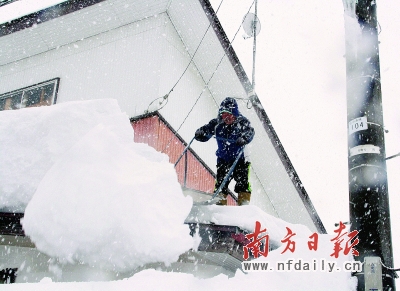 一男子在日本新潟县十日町清扫屋顶上的积雪。新华社发